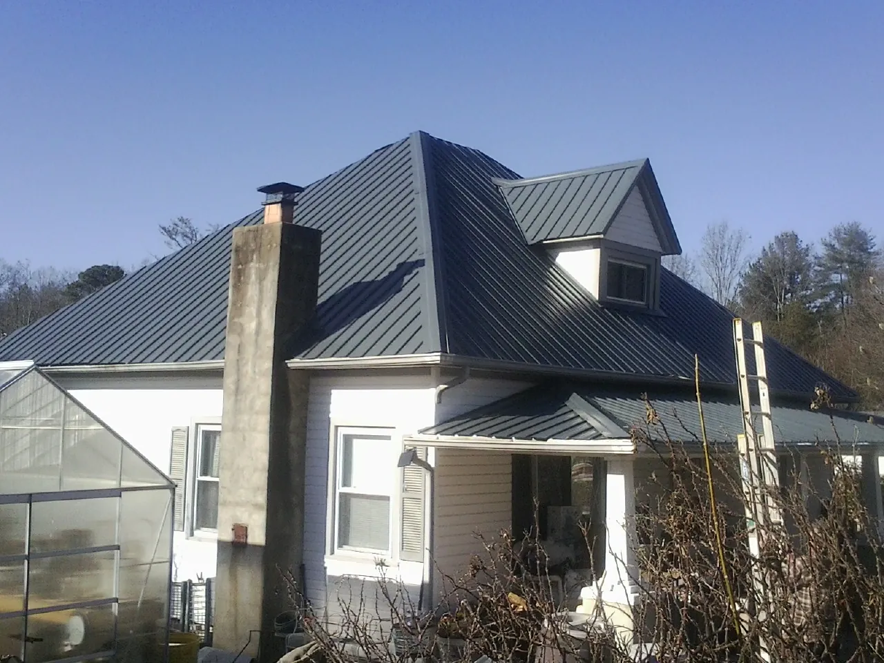 Dark blue standing seam metal roof on a white farmhouse with dormer — Slate & Tile Roof Repair by Roofing Brothers in Fork Union