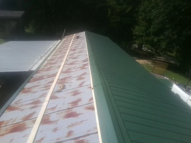 Old rusted panels beside newly installed green metal roofing — Wind Damage Roof Repair by Roofing Brothers in Fork Union