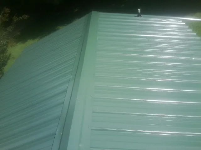 New green metal panels meeting at the ridge of a roof — Flat Roof Repair work by our crew in Fork Union