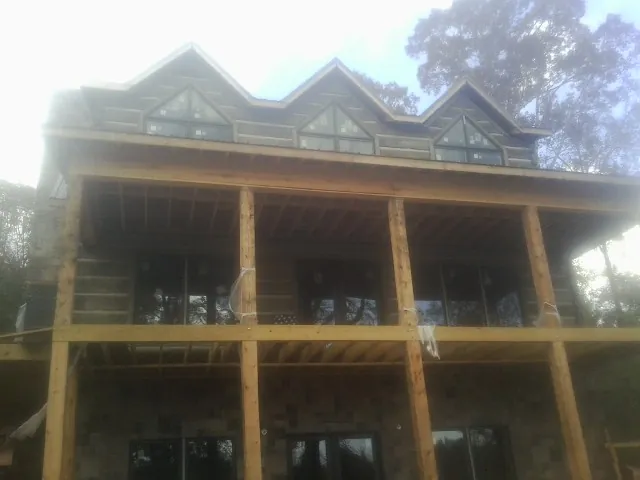 Dormers and porch framing on a large log home under construction — Roof Coating work by our crew in Fork Union