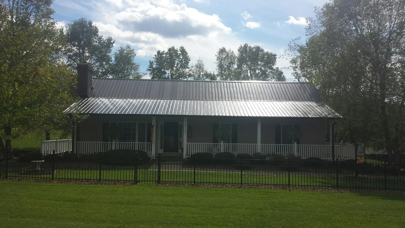 Gray metal roof on a brick ranch with a full width front porch — Gutter Guard Installation work by our crew in Fork Union