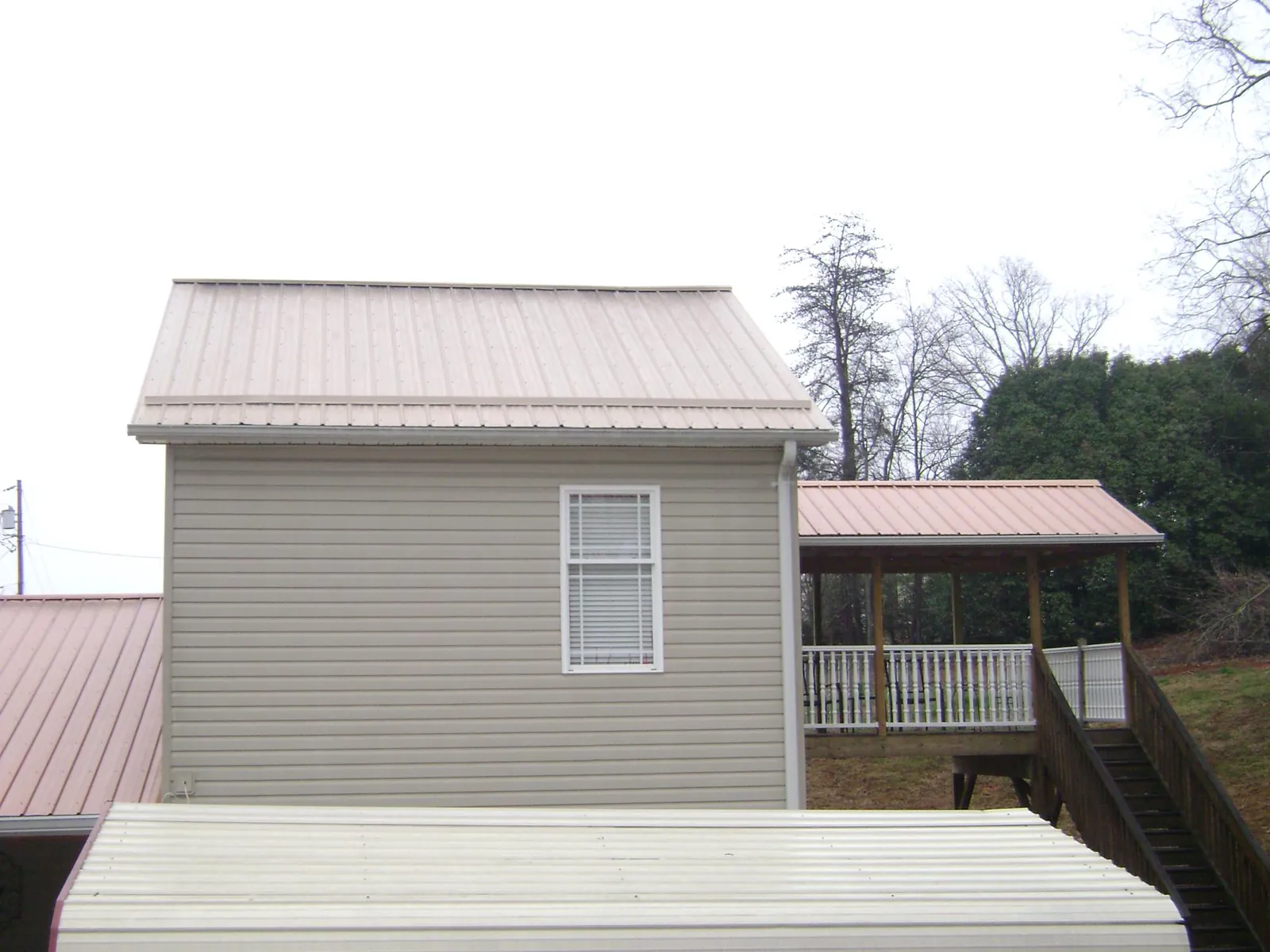 Tan metal roofs on a two story addition and attached porch, from a Roof Replacement job in Fork Union