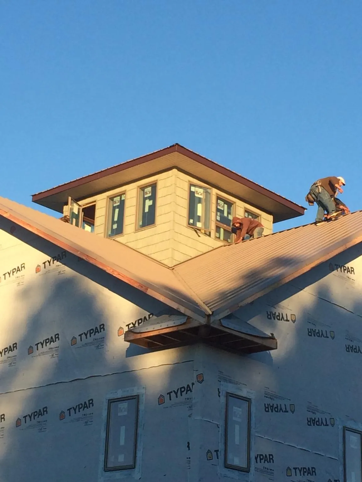 Roofers working around a rooftop cupola on a new metal roof at sunset — Roof Waterproofing in Fork Union by Roofing Brothers